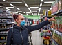 Eine Frau mit Einwegmaske greift in einem Supermarkt in ein Regal.